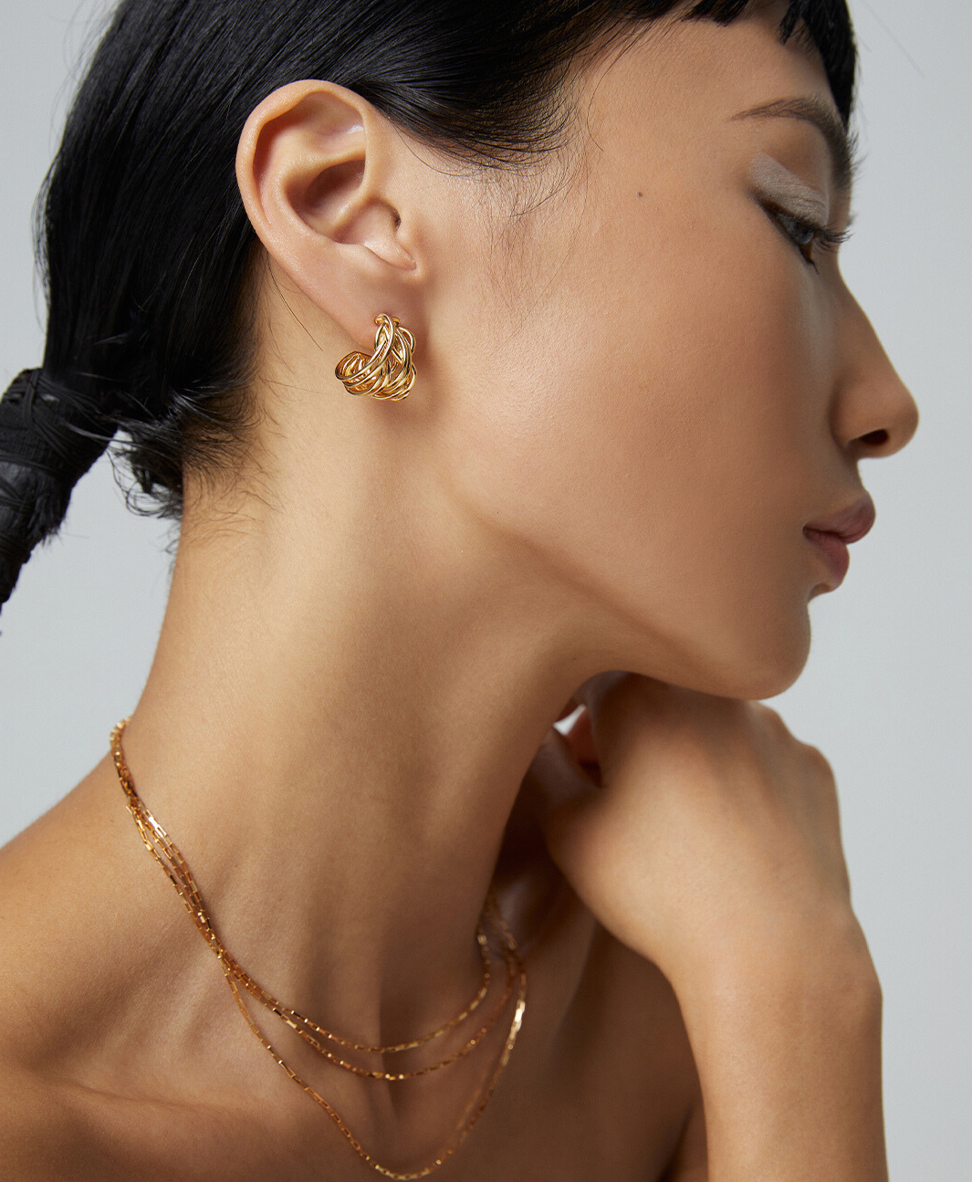 An edgy woman adorned with gold jewelry, showcasing her unique style.