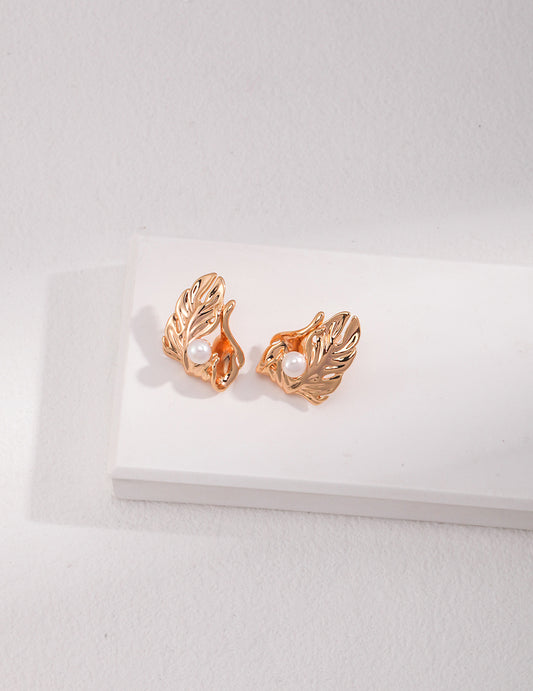 A pair of gold tone earrings adorned with delicate leaf motifs, perfect for adding a touch of nature to any outfit.