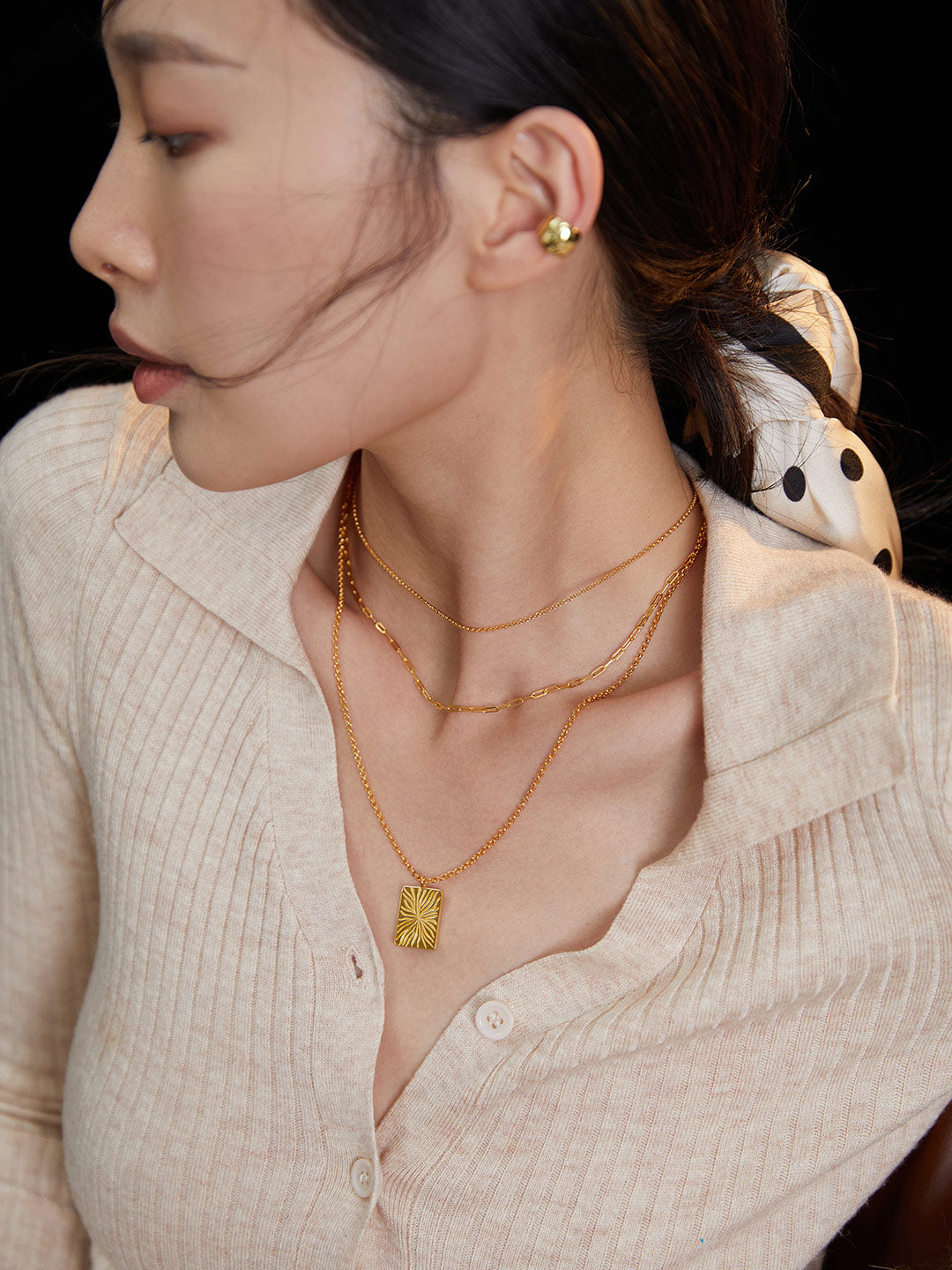 A woman wearing a gold necklace and earrings, accentuating her beauty with a touch of elegance and luxury.