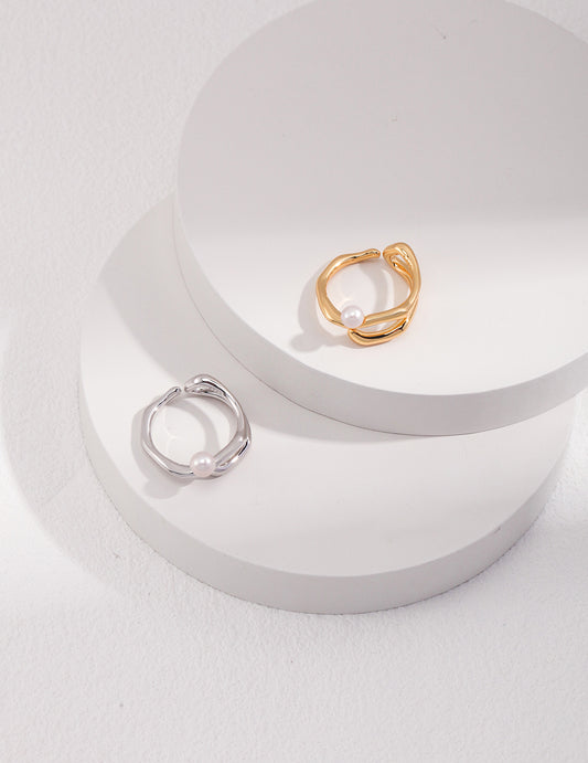 Two unique silver and gold rings with freshwater pearl, elegantly displayed on a white surface.