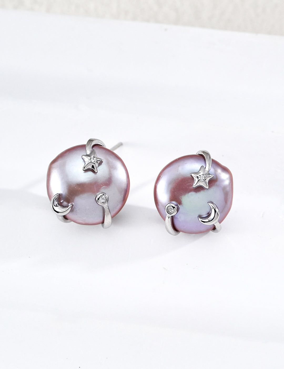 A sharp product shot displaying the silver Vesper Studs, highlighting the luminous coin pearl and the intricate star and moon setting.