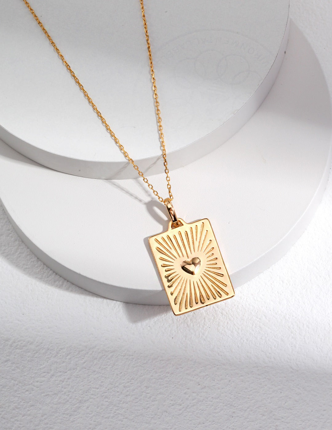 A gold plated pendant necklace featuring a striking sunburst design and a delicate heart, radiating elegance and style.