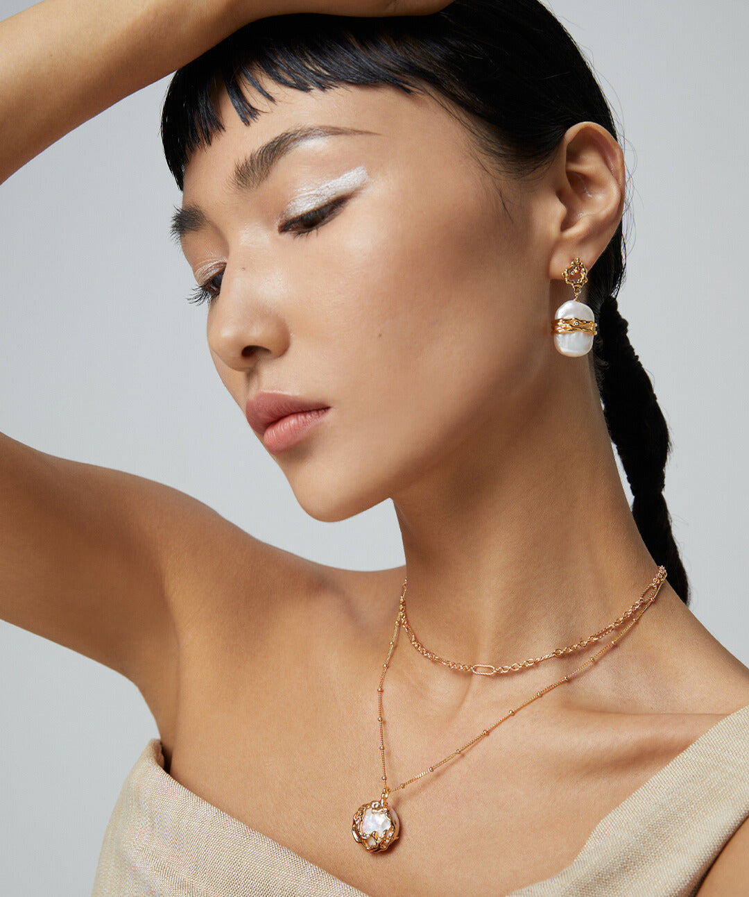 A model showcasing lustrous freshwater pearls earrings and necklace in gold.