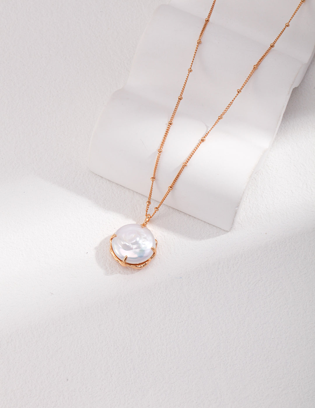 Stunning white pearl necklace resting on white table