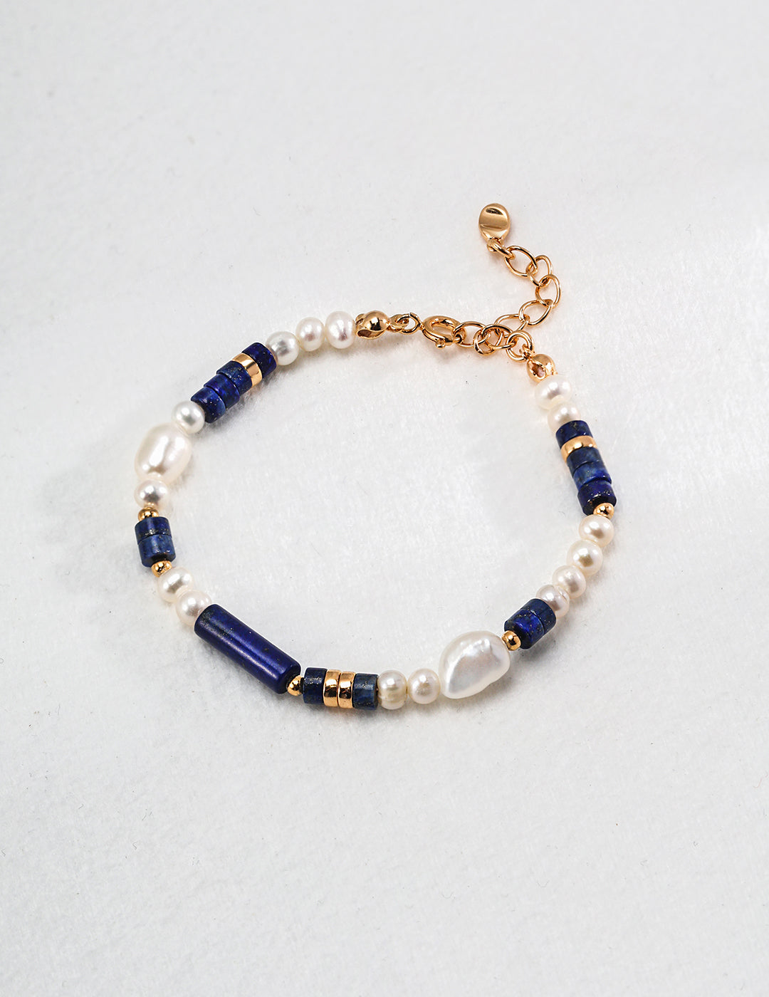 Blue and white bead bracelet with gold plated charms, featuring freshwater pearls and lapis lazuli.