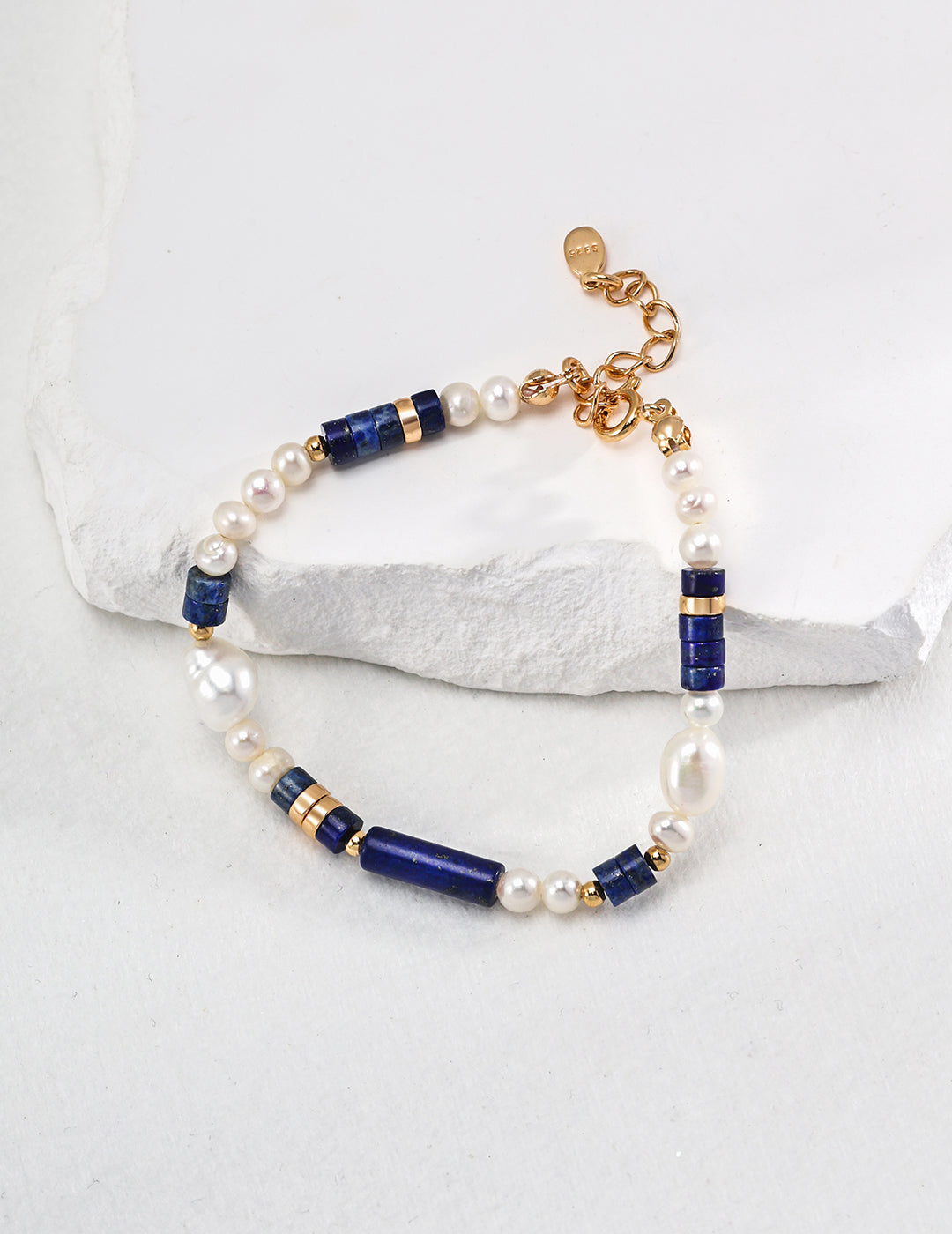 A stunning blue and white bracelet adorned with gold beads and pearls, featuring freshwater pearls and lapis lazuli.