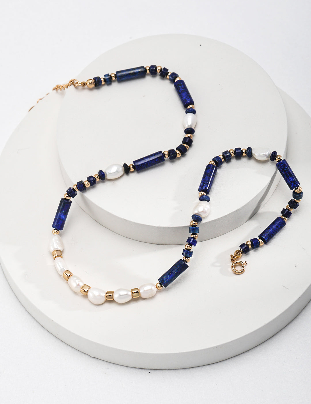 An elegant necklace made of lapis lazuli and adorned with dainty freshwater pearls in blue and white.