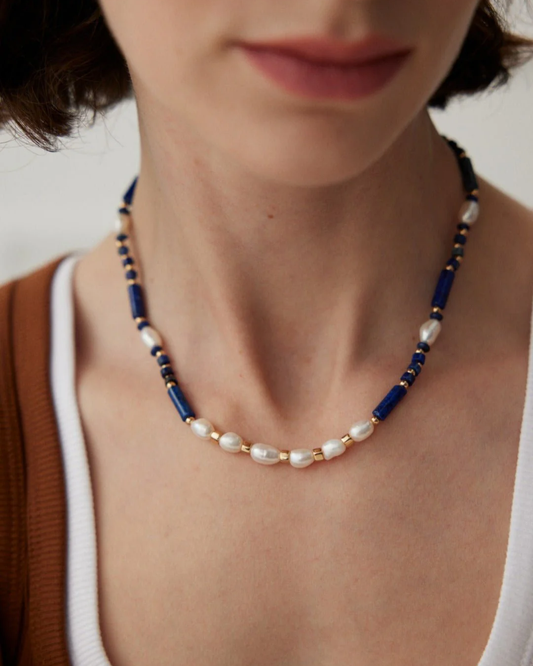 A woman displays a beautiful lapis lazuli necklace in blue and white, enhancing her style with its rich colors.