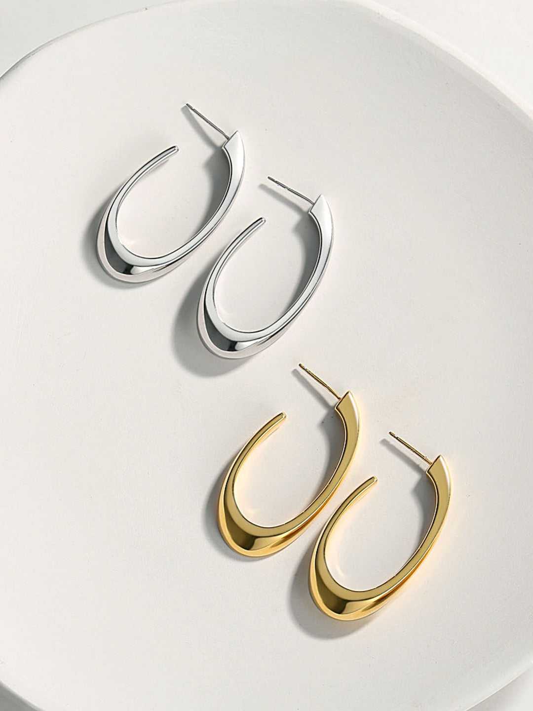 Two pairs of elegant hoop earrings, one in gold and the other in silver, beautifully complementing each other.