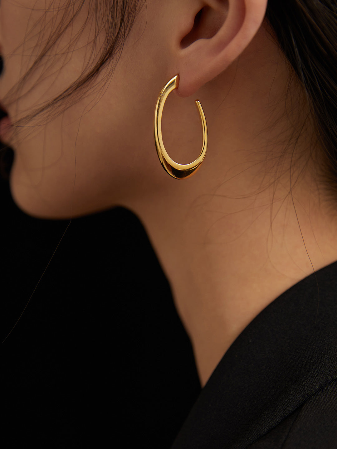 Model wearing gold hoop earrings with a curved shape, beautifully designed.