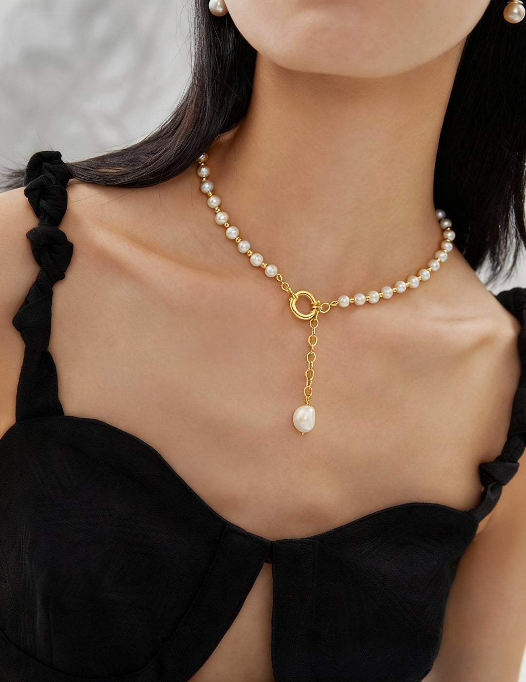 Lifestyle shot of a woman wearing the gold Willow pearl necklace, highlighting the elegant lariat-style drop and executive aesthetic.