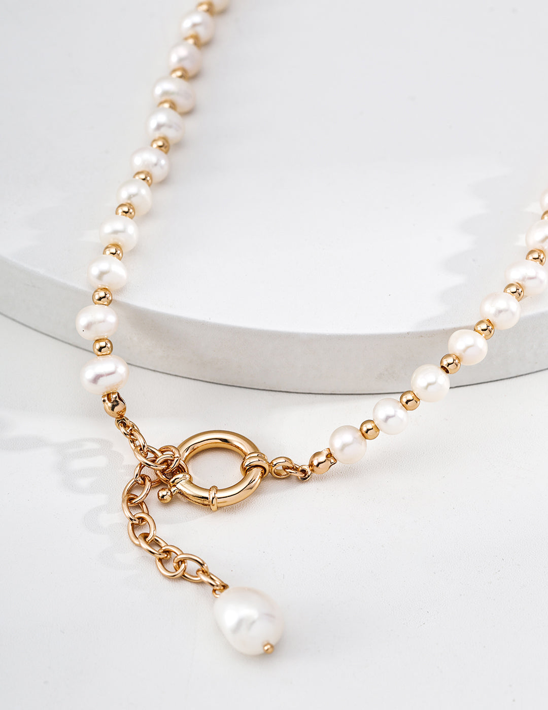 Macro shot of the 18k gold vermeil toggle and the organic freshwater pearl drop of the Mezuille Willow necklace.