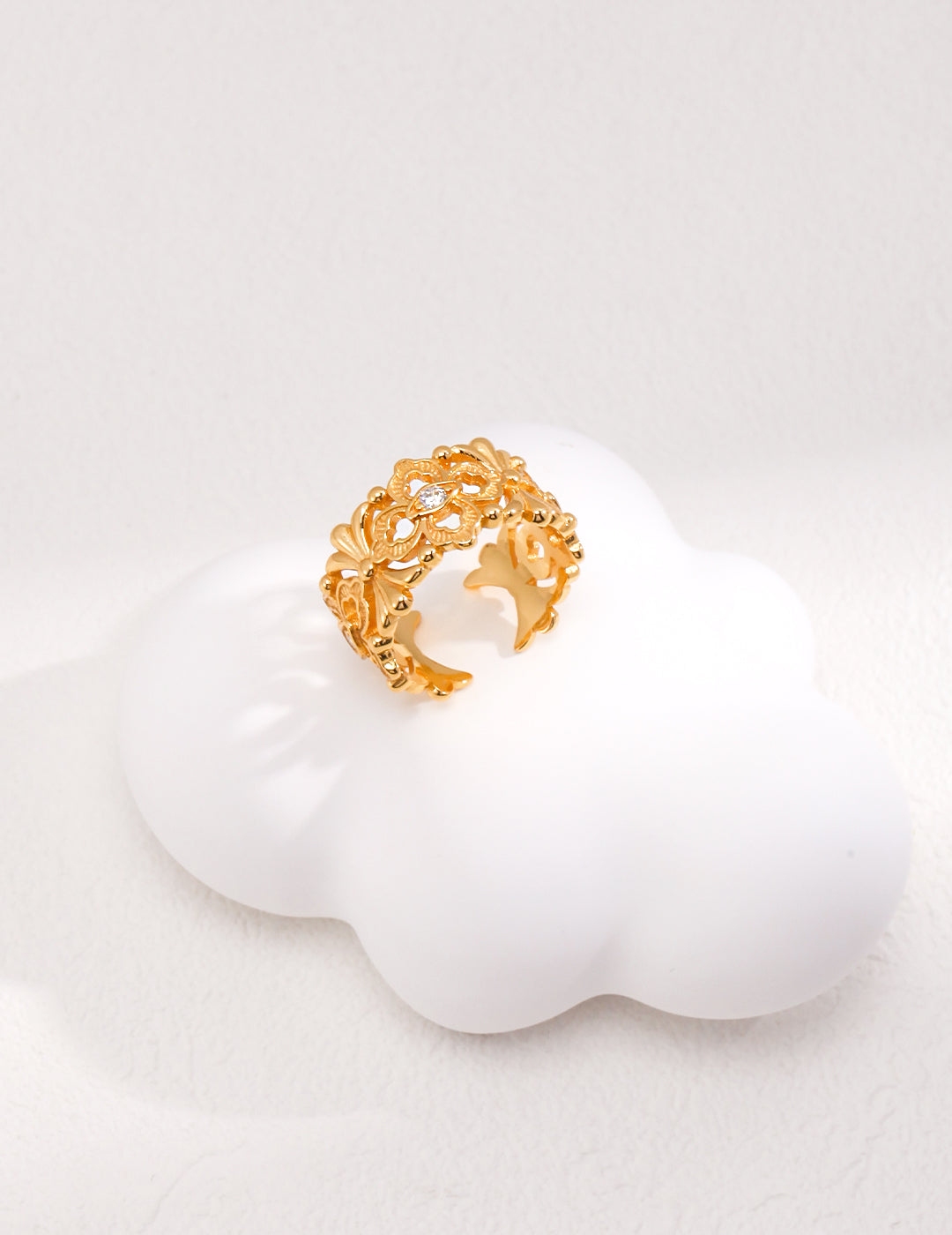 Shiny gold ring with cubic zirconia perched on soft cloud.