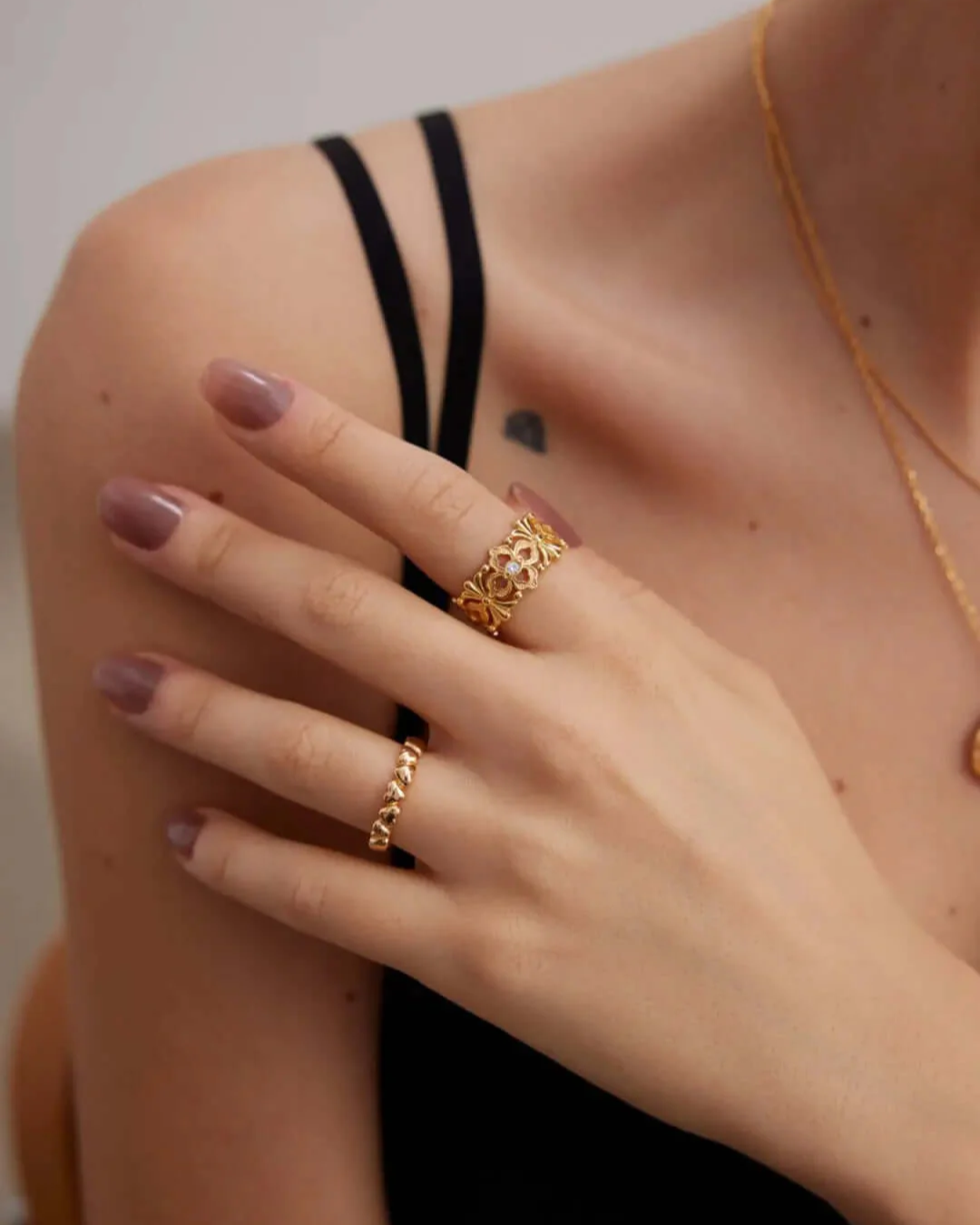 A woman displaying a gold chain and her gold rings, highlighting her chic and fashionable style.