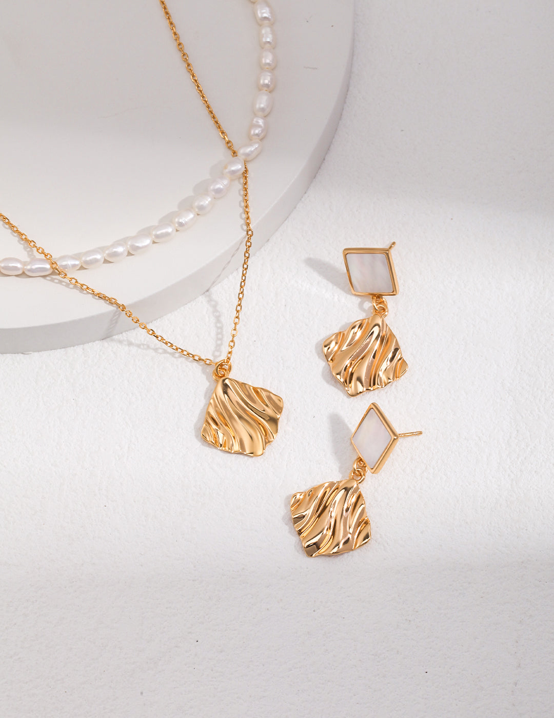 A stunning gold plated necklace and earrings set with a beautiful wavy design and gold nacre accents.