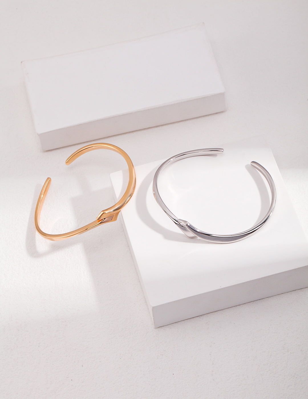 Two bangles on a white surface - a stunning combination of silver and gold jewelry.