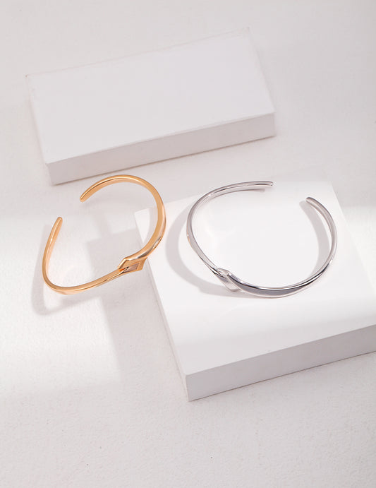 Two bangles on a white surface - a stunning combination of silver and gold jewelry.