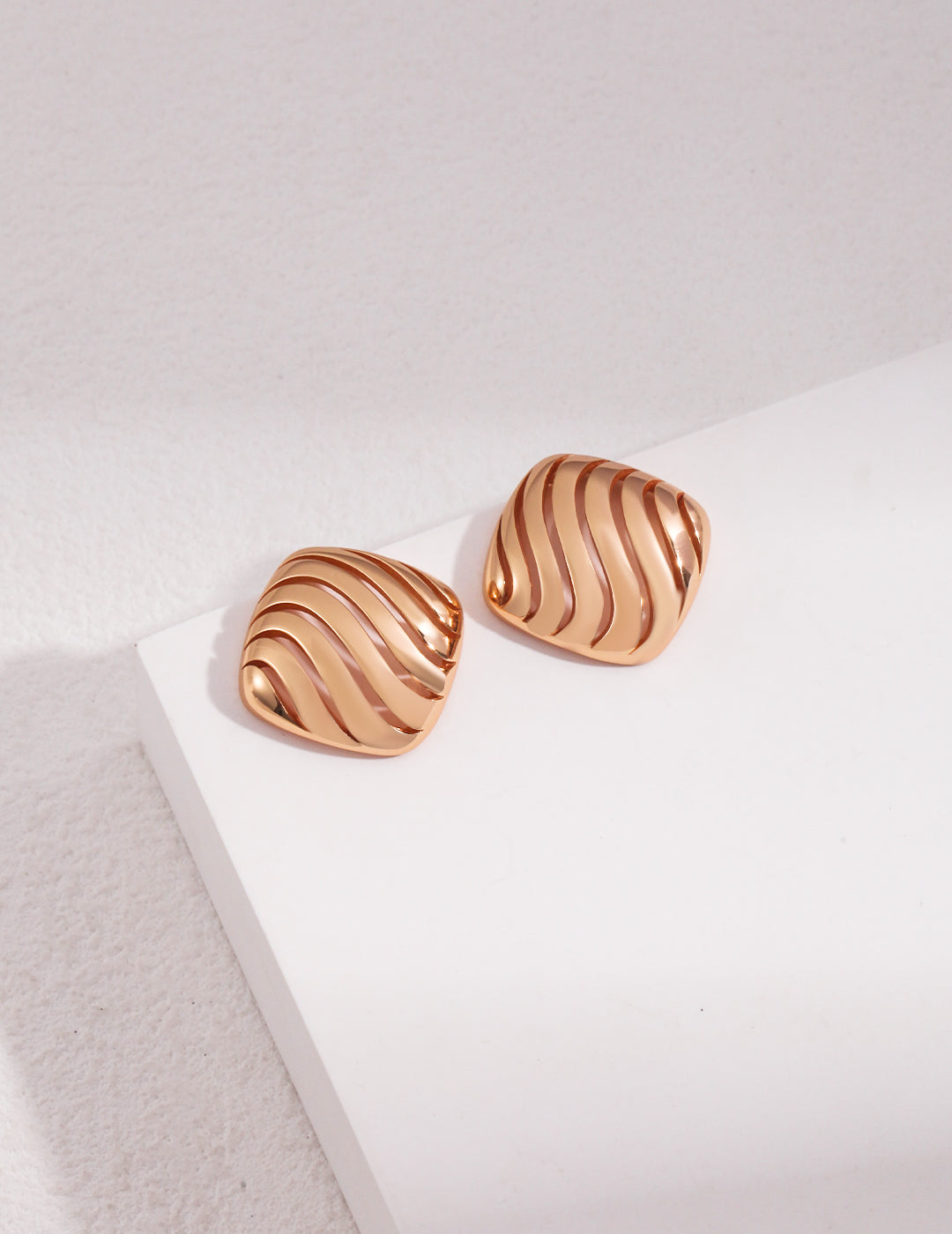 Gold plated earrings with a hollow wave pattern.