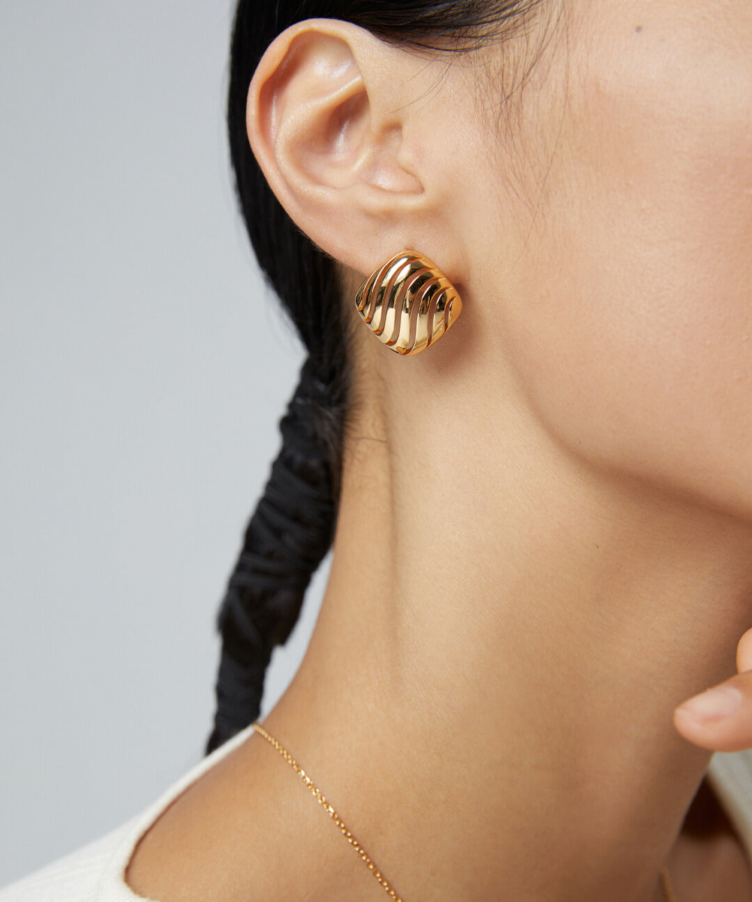 A model wearing gold hollow striped earrings, enhancing her look with a touch of elegance and style.