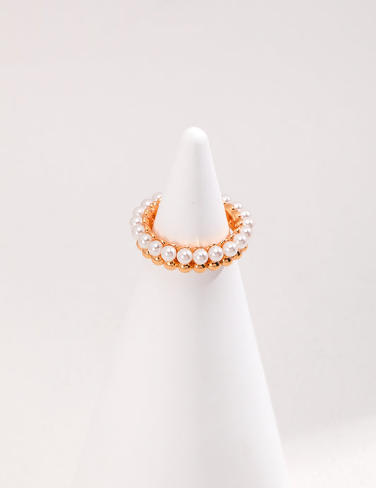 A white cone with a gold plated ring on top, adorned with pearls.