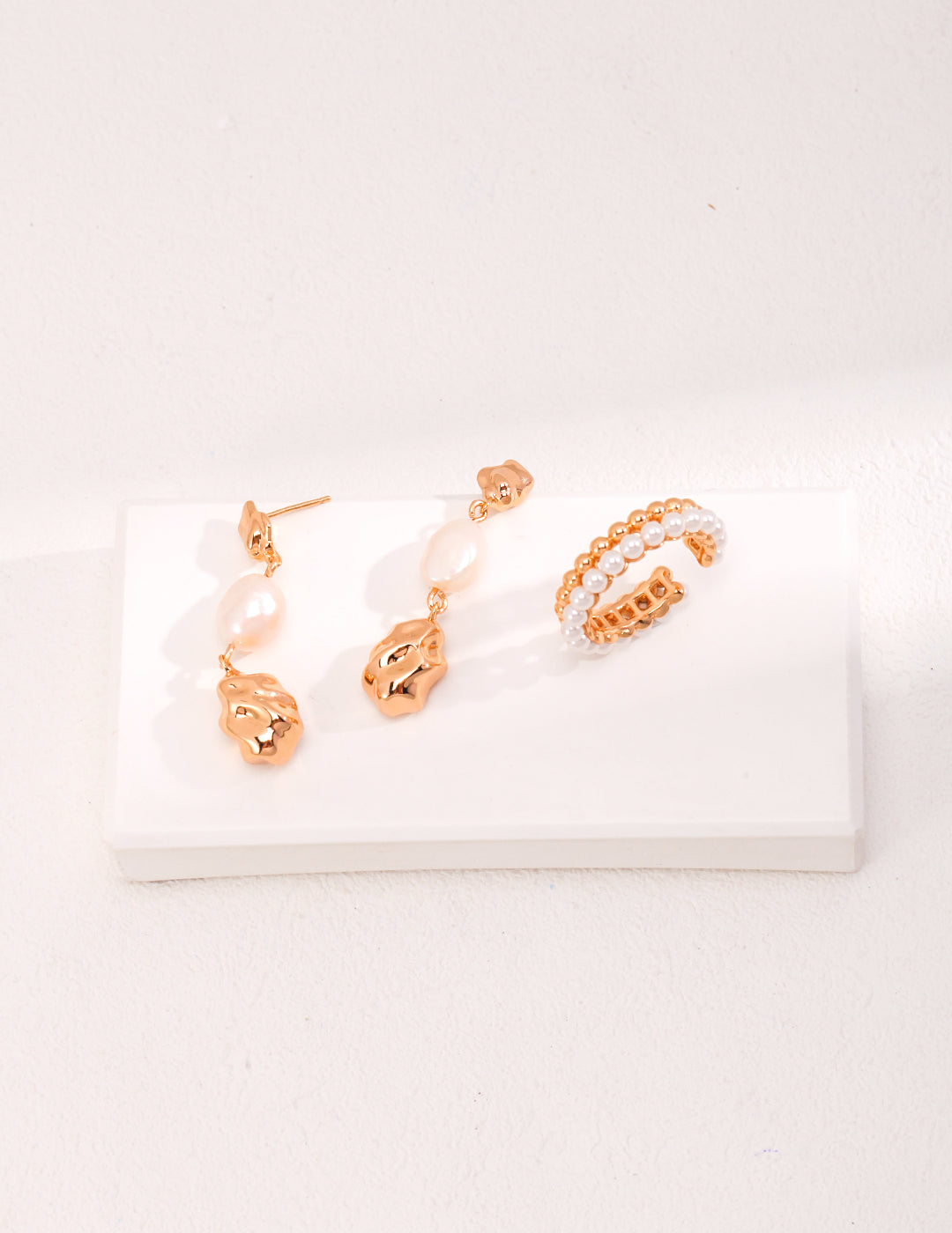 A stunning pair of gold earrings complemented by a beautiful white pearl ring.