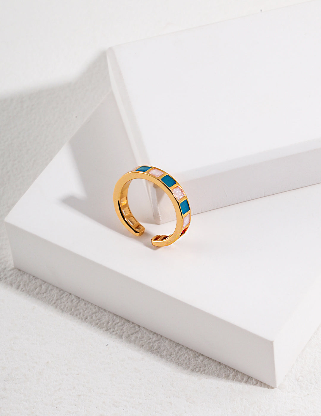 A gold plated ring with vibrant blue and green enamel design.