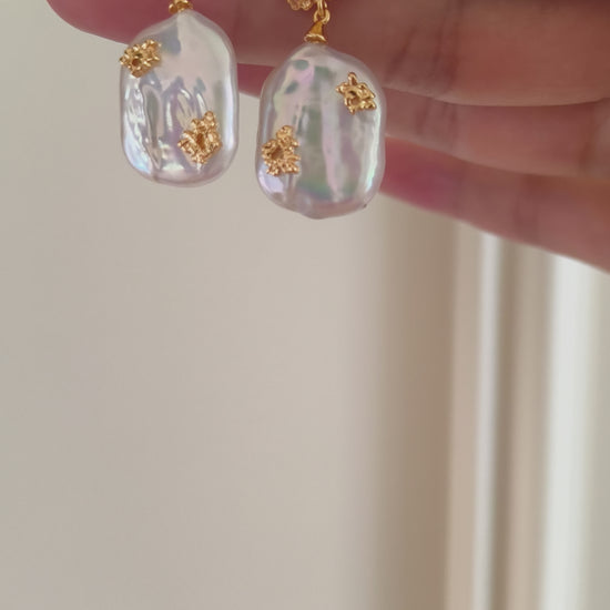 Close up of a pair of imperfect pearl drop earrings by Mezuille displaying details.