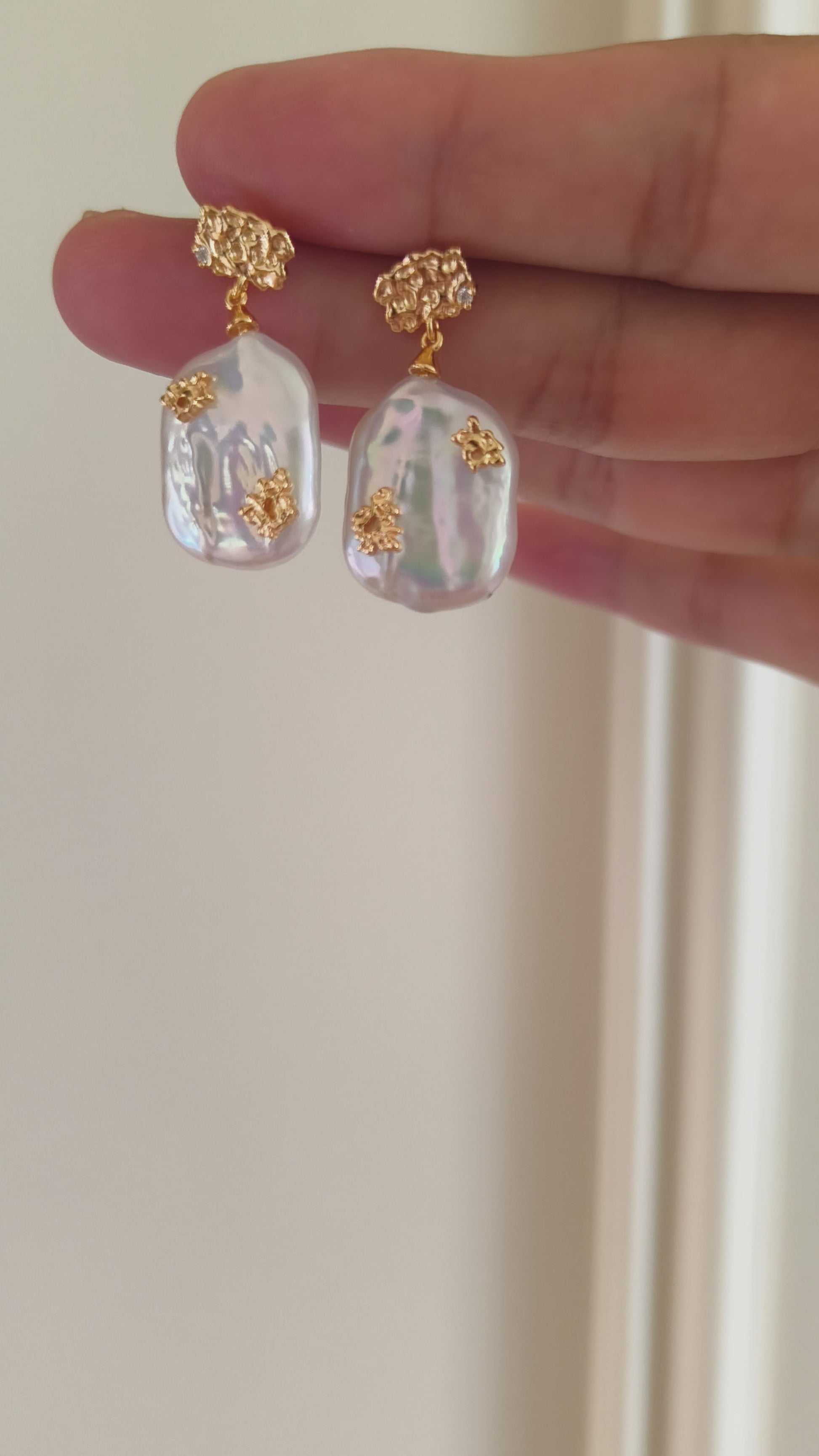 Close up of a pair of imperfect pearl drop earrings by Mezuille displaying details.